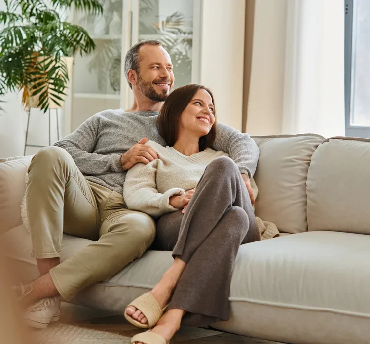 Frau und Man lächelnd gemeinsam auf einer Couch