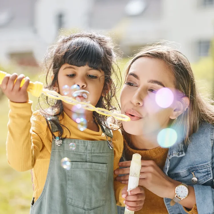 Junge Frau und Mädchen pusten Seifenblasen - Nanny