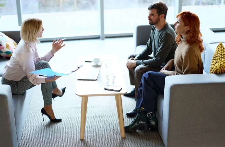Gesprächssituation: Frau sitz einem Paar gegenüber dazwischen ein Tisch